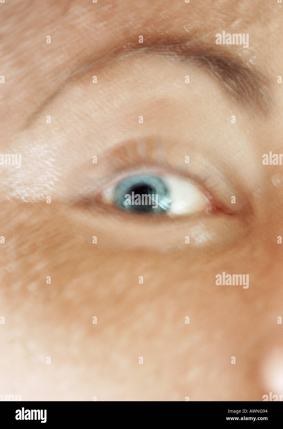 Woman's blue eye and raised eyebrow, close up, blurred. Stock Photo