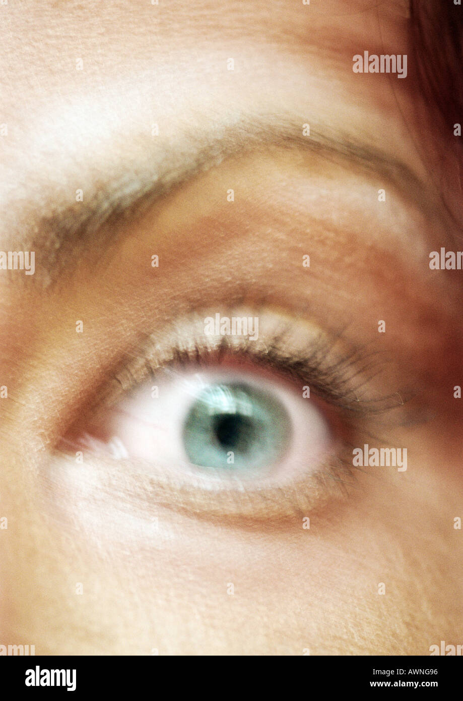 Woman's green eye and raised eyebrow, close-up, blurred. Stock Photo