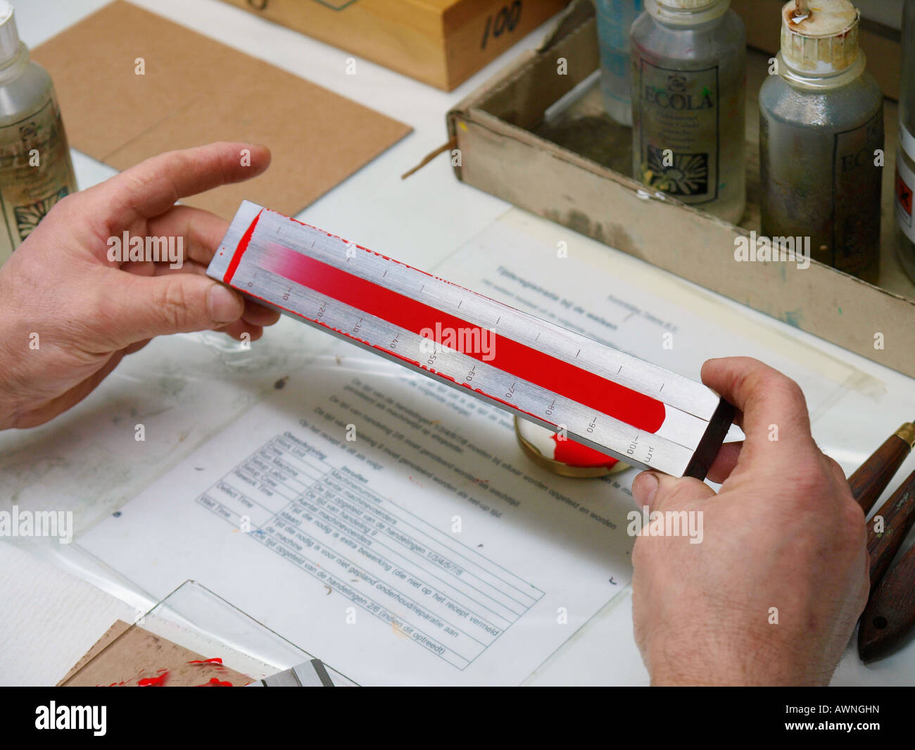 Reading Hegman test to determine particle size of red paint in a paint factory of Talens Apeldoorn the Netherlands Stock Photo