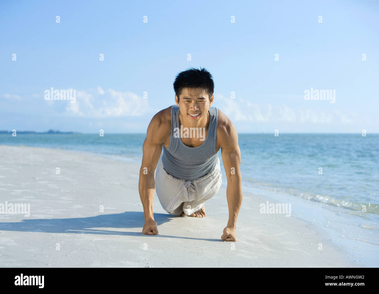Man doing push-ups on beach Stock Photo