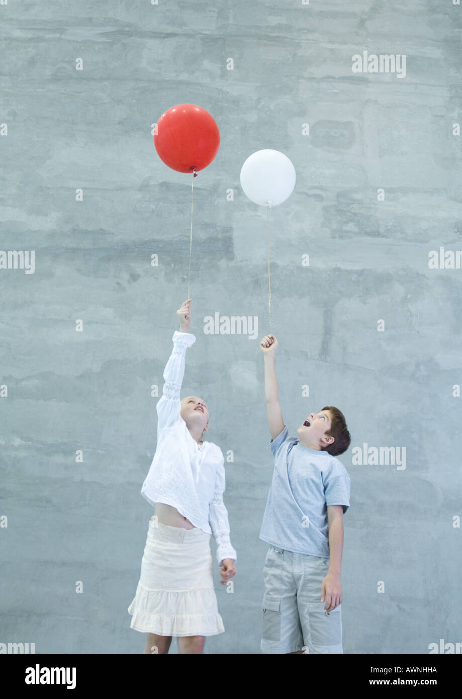 Two children holding helium balloons Stock Photo