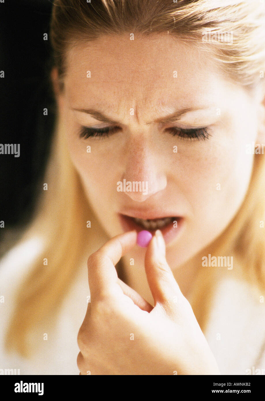 Woman putting pill in mouth, close-up Stock Photo