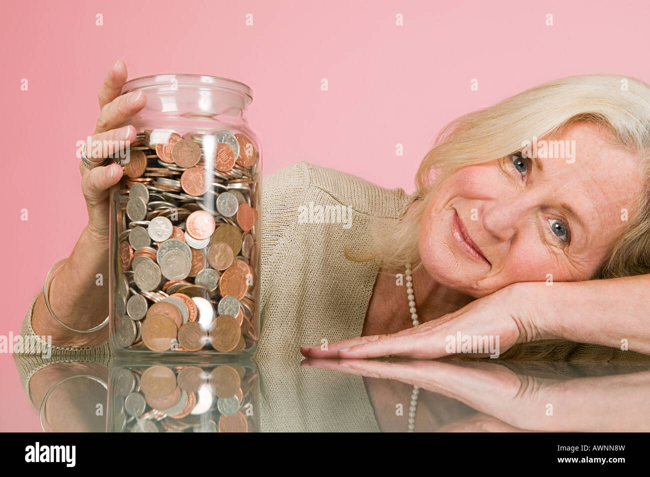 Woman with coins in a jar Stock Photo