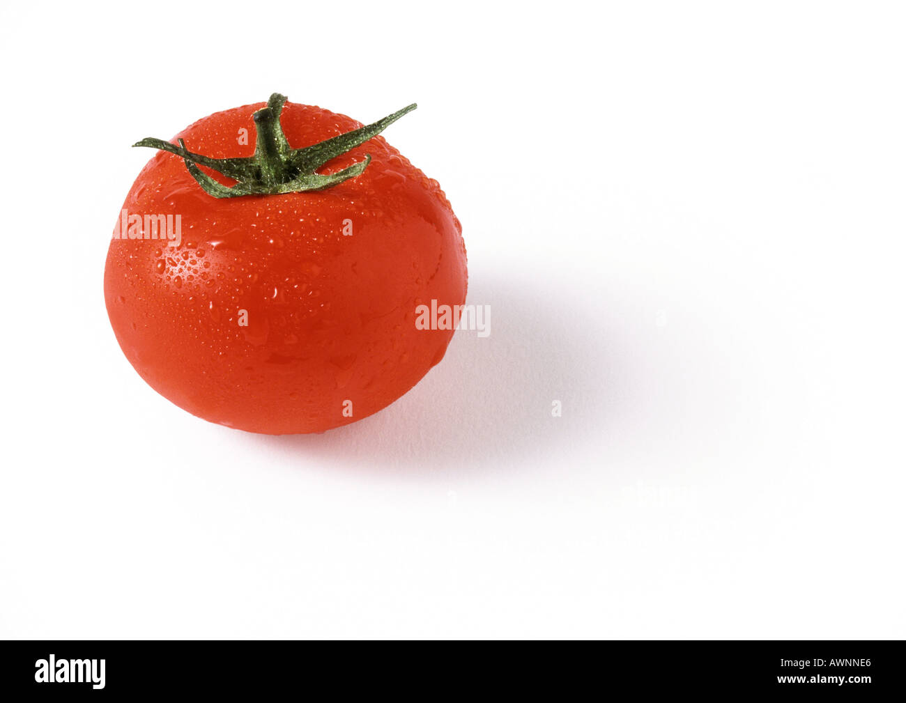 Tomato with stem, covered with droplets of water, close-up Stock Photo