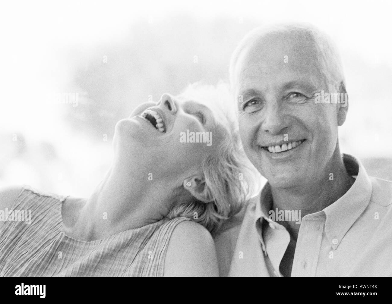 Mature man and woman smiling, woman with head back, close-up, B&W Stock Photo