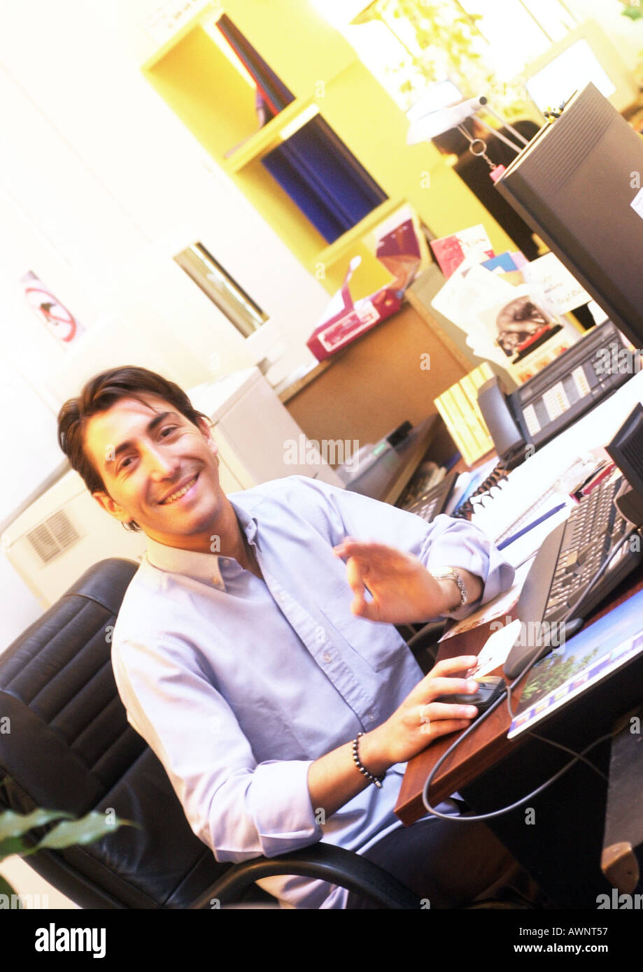 Man working at desk in office, smiling at camera Stock Photo