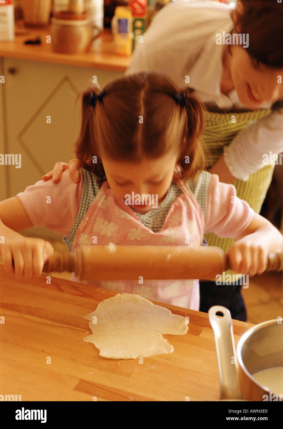 Girl using rolling pin, woman looking over girl's shoulder Stock Photo Alamy