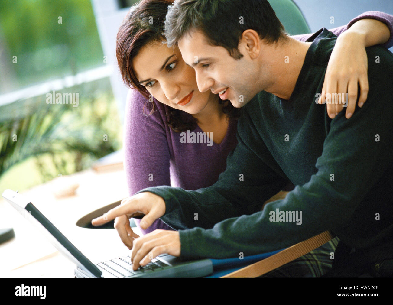 Man using laptop computer, woman sitting with arm around him Stock ...