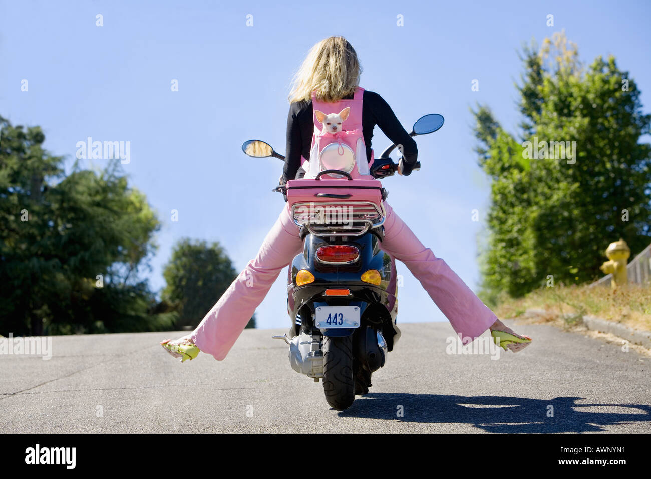 Woman riding a scooter with extended legs Stock Photo