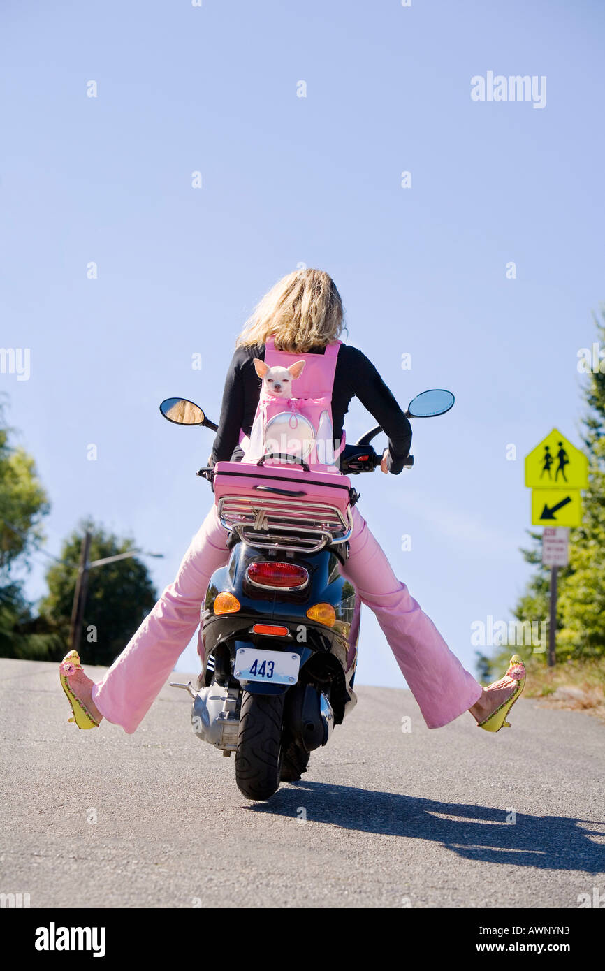 Woman riding a scooter with extended legs Stock Photo