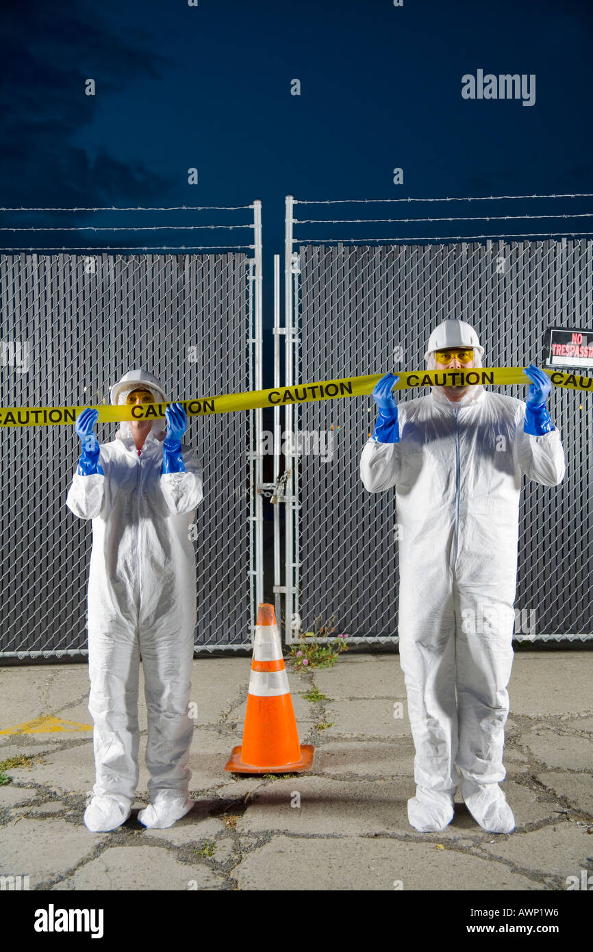 People in biohazard suits standing behind caution tape Stock Photo - Alamy