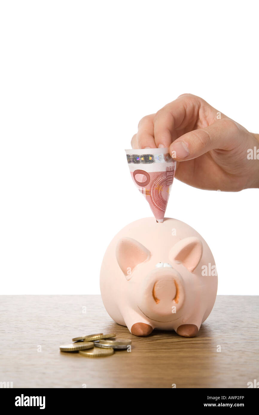 Hand pulling cash from a piggy bank Stock Photo