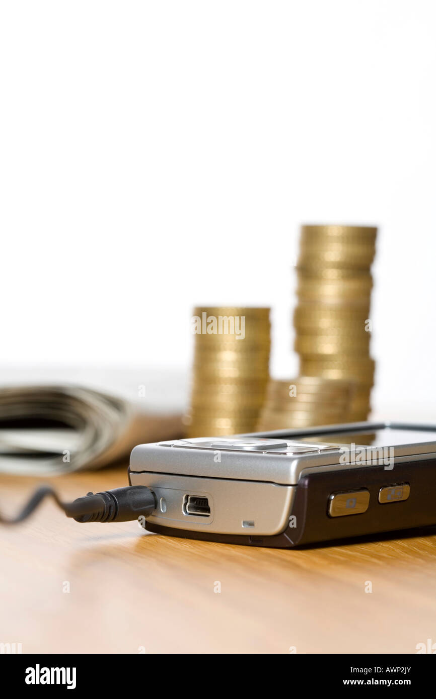 Mobile phone in front of stacked coins Stock Photo