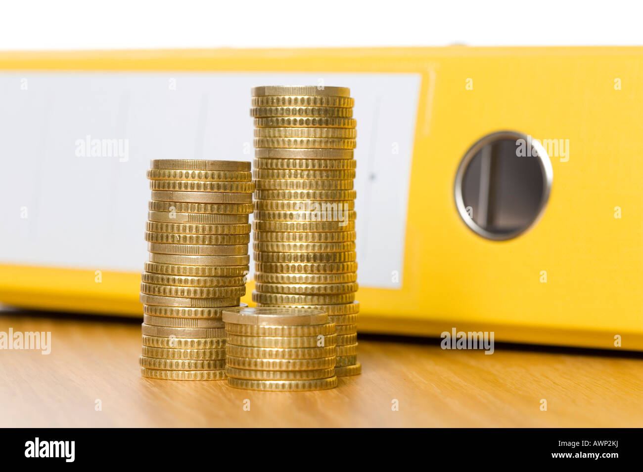 Coins stacked in front of a file folder Stock Photo
