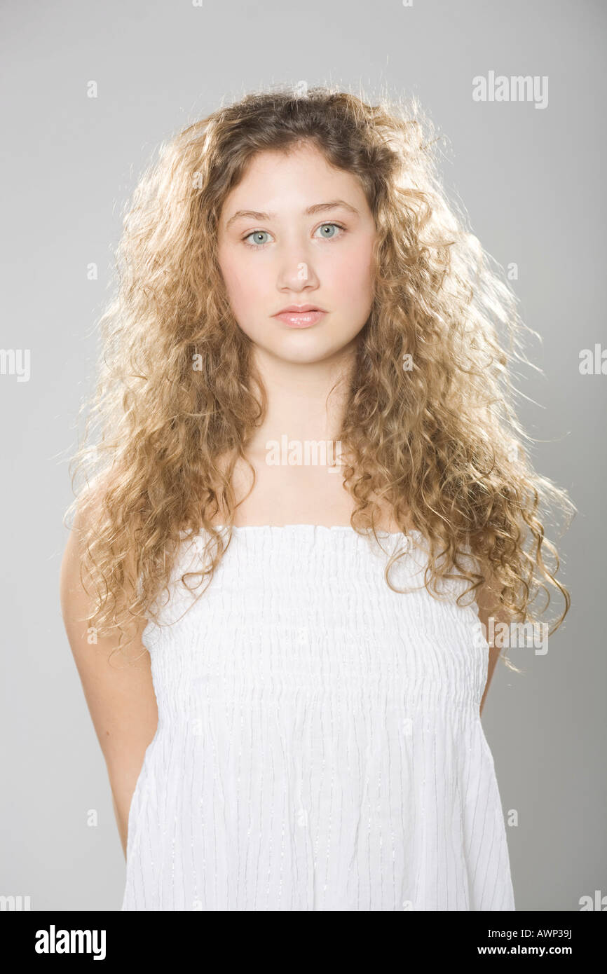 Young woman with long, curly hair wearing a white dress Stock 