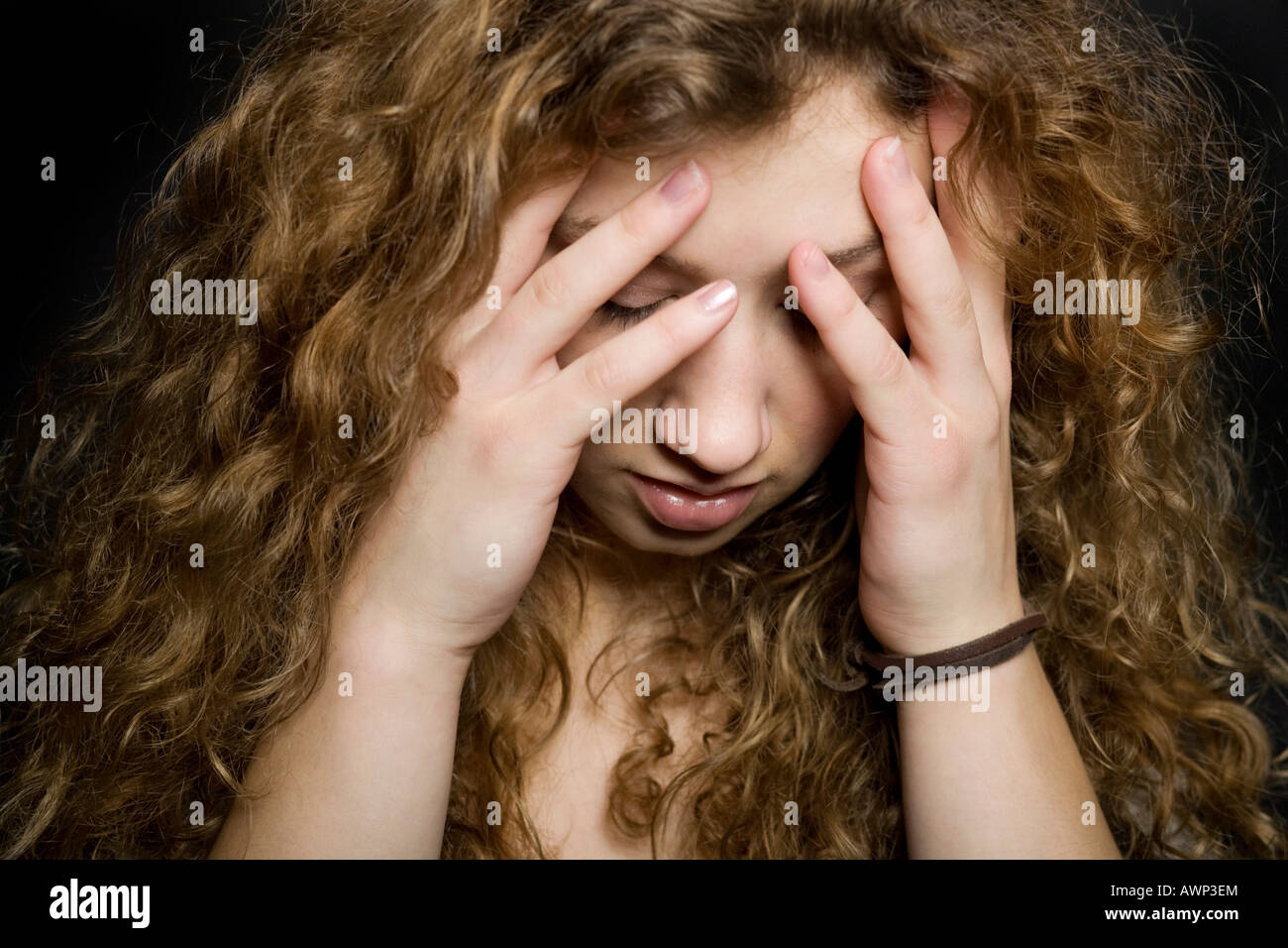 Distraught young woman holding her hands to her face Stock Photo