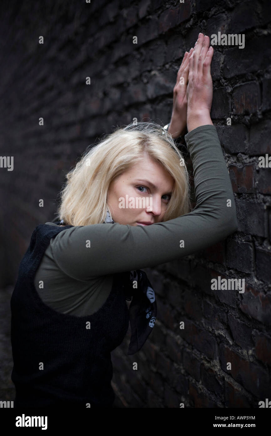 Blonde woman standing in front of a stone wall Stock Photo - Alamy