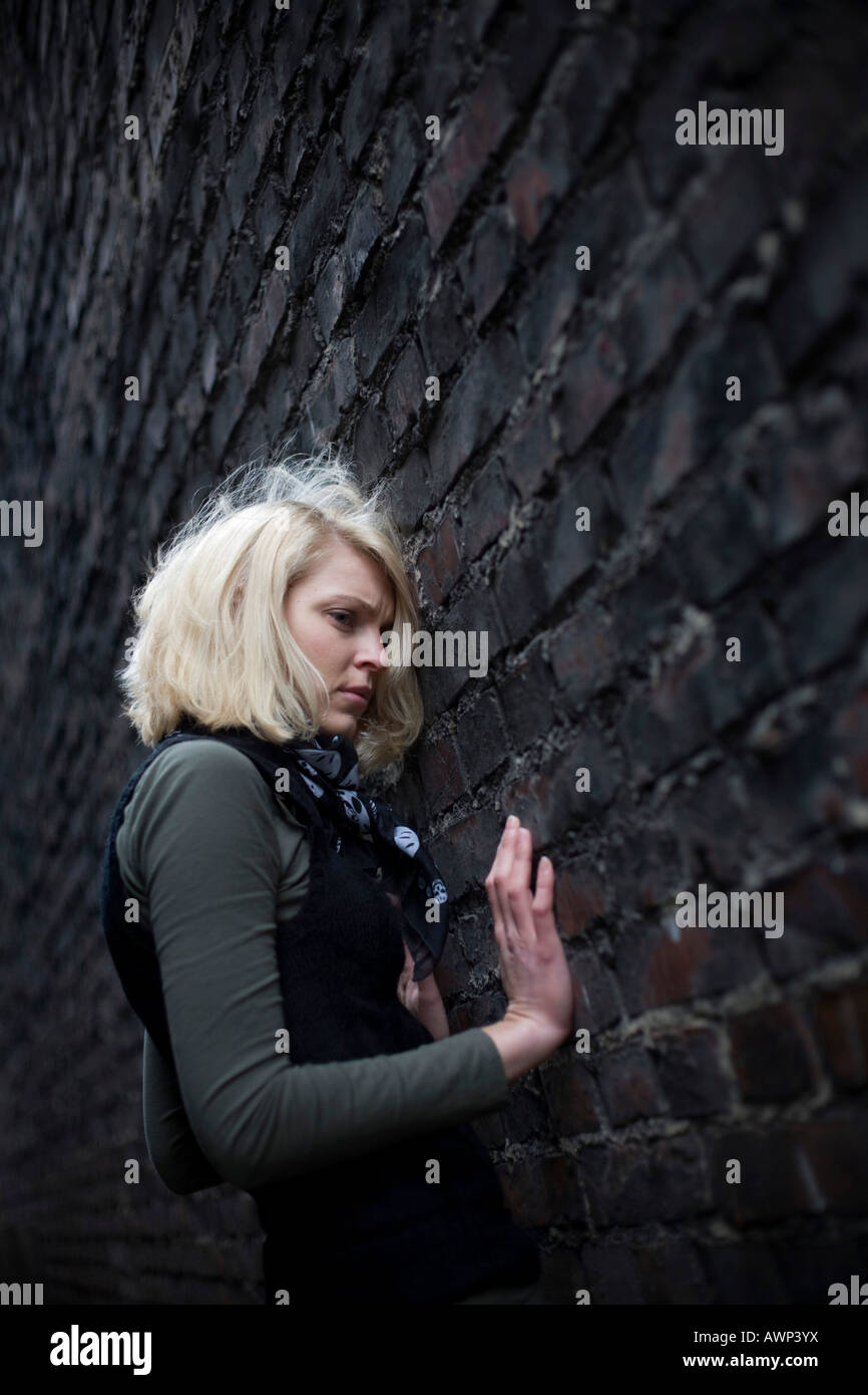 Blonde woman standing in front of a stone wall Stock Photo - Alamy