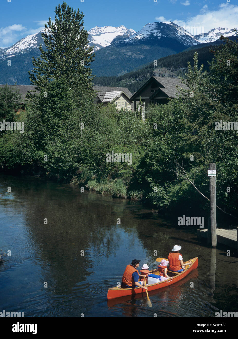Family of four paddling a red canoe on River of Golden Dreams with snow
