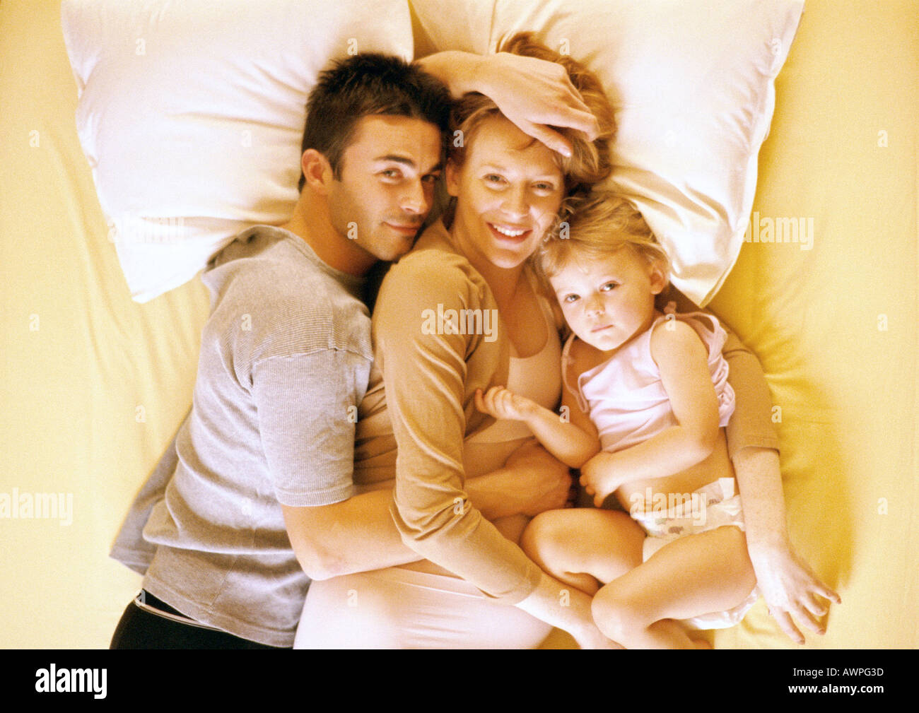 Couple and child lying on bed, elevated view, portrait Stock Photo
