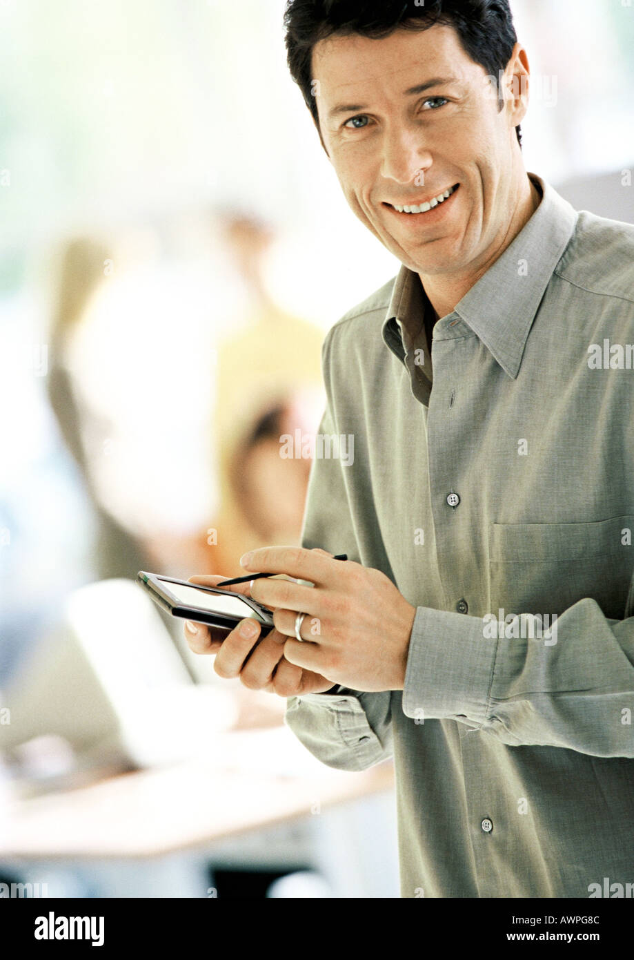 Businessman using pocket computer, smiling, portrait Stock Photo