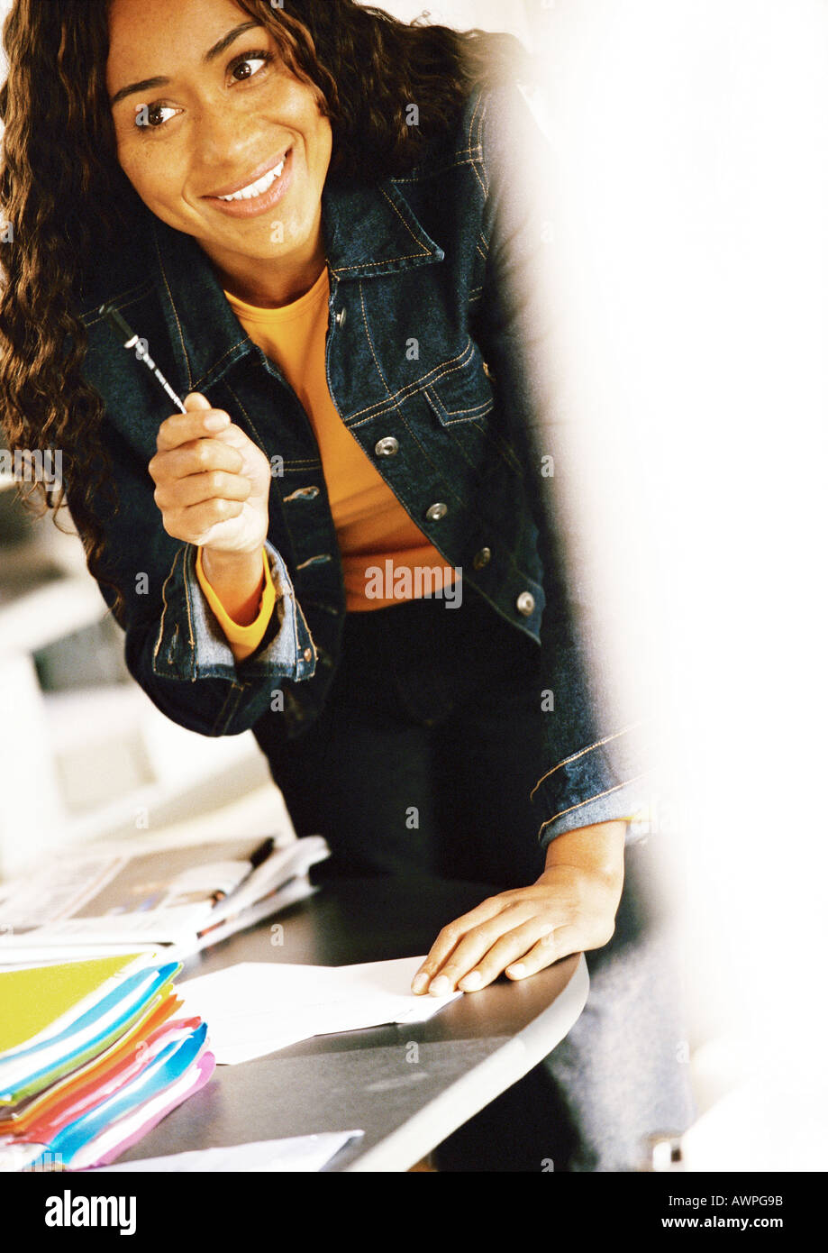 Woman holding pen, smiling Stock Photo