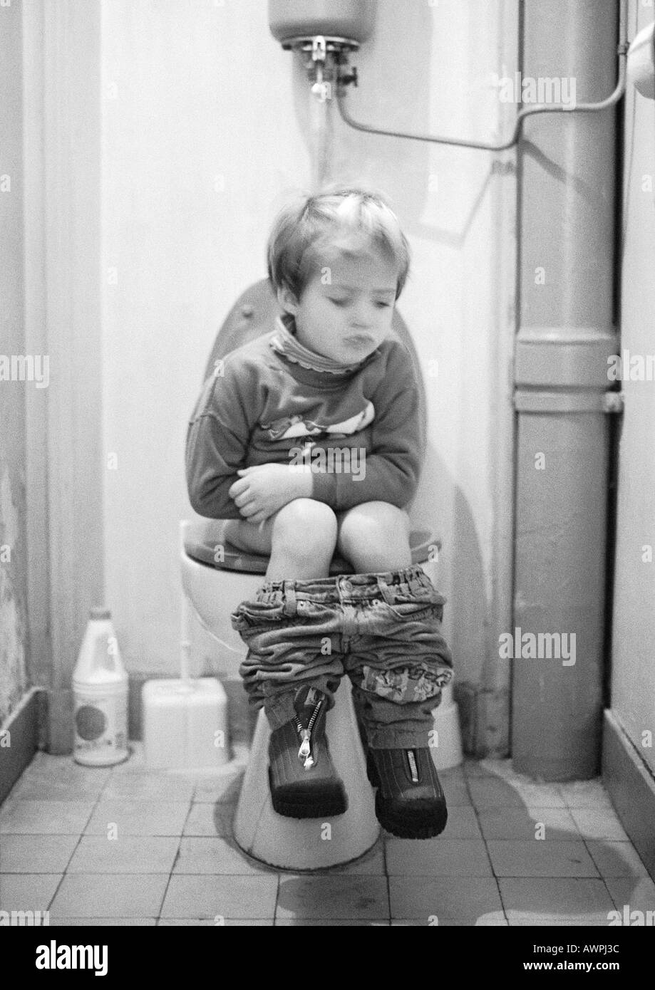 Little girl sitting on toilet, b&w Stock Photo