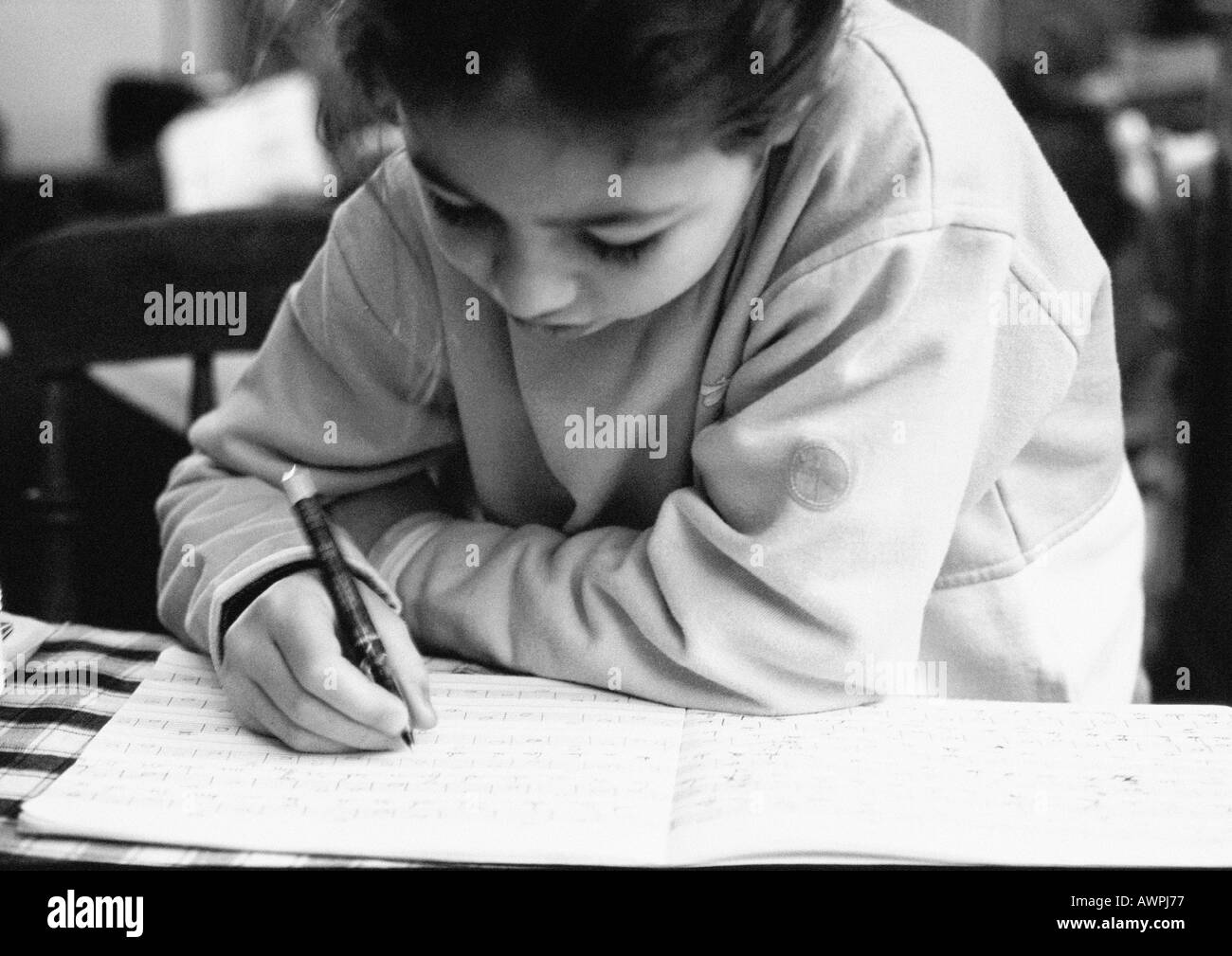 Child bending head over notebook, writing, close-up Stock Photo