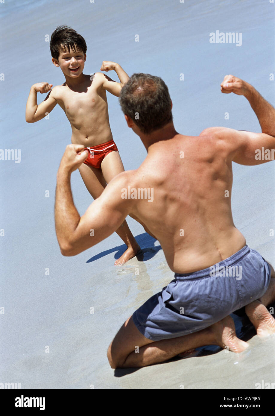 Man and child facing each other, flexing on beach Stock Photo - Alamy