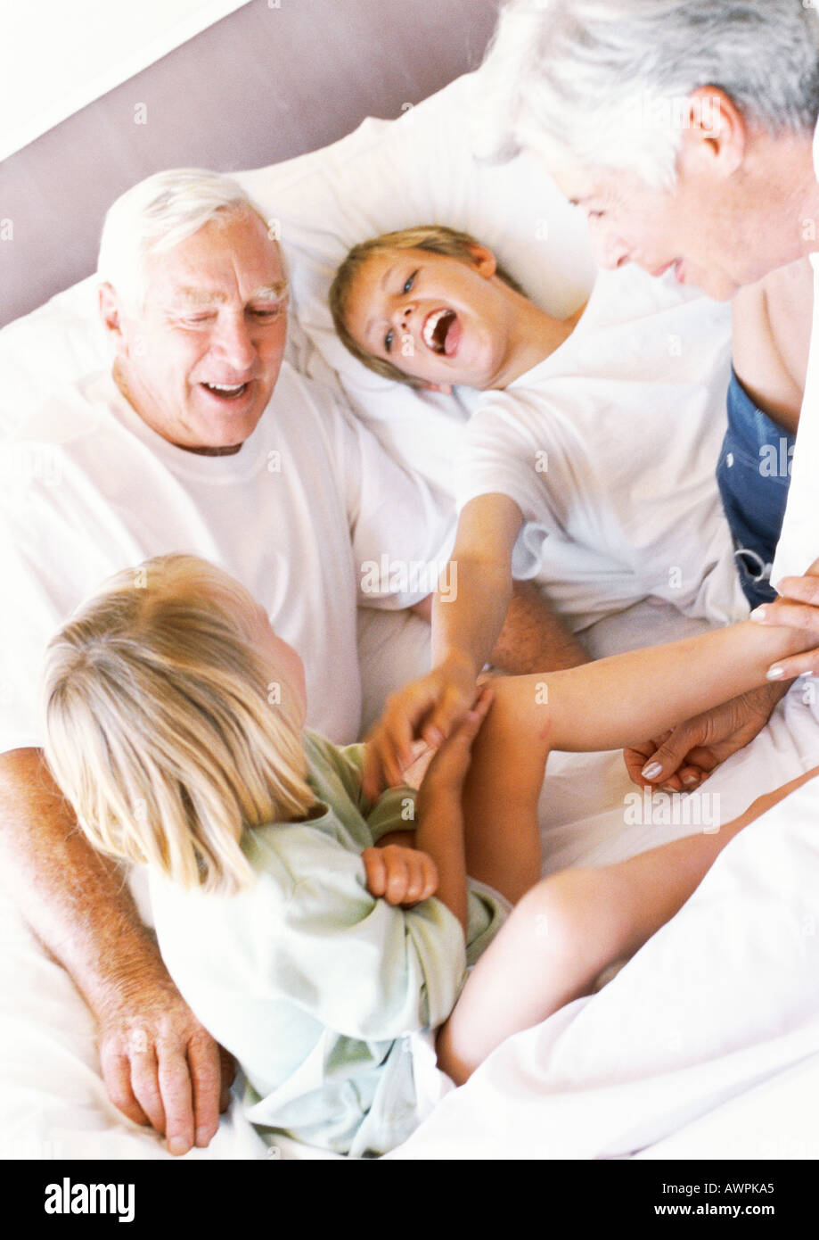 Grandparents and children playing on bed, smiling Stock Photo Alamy
