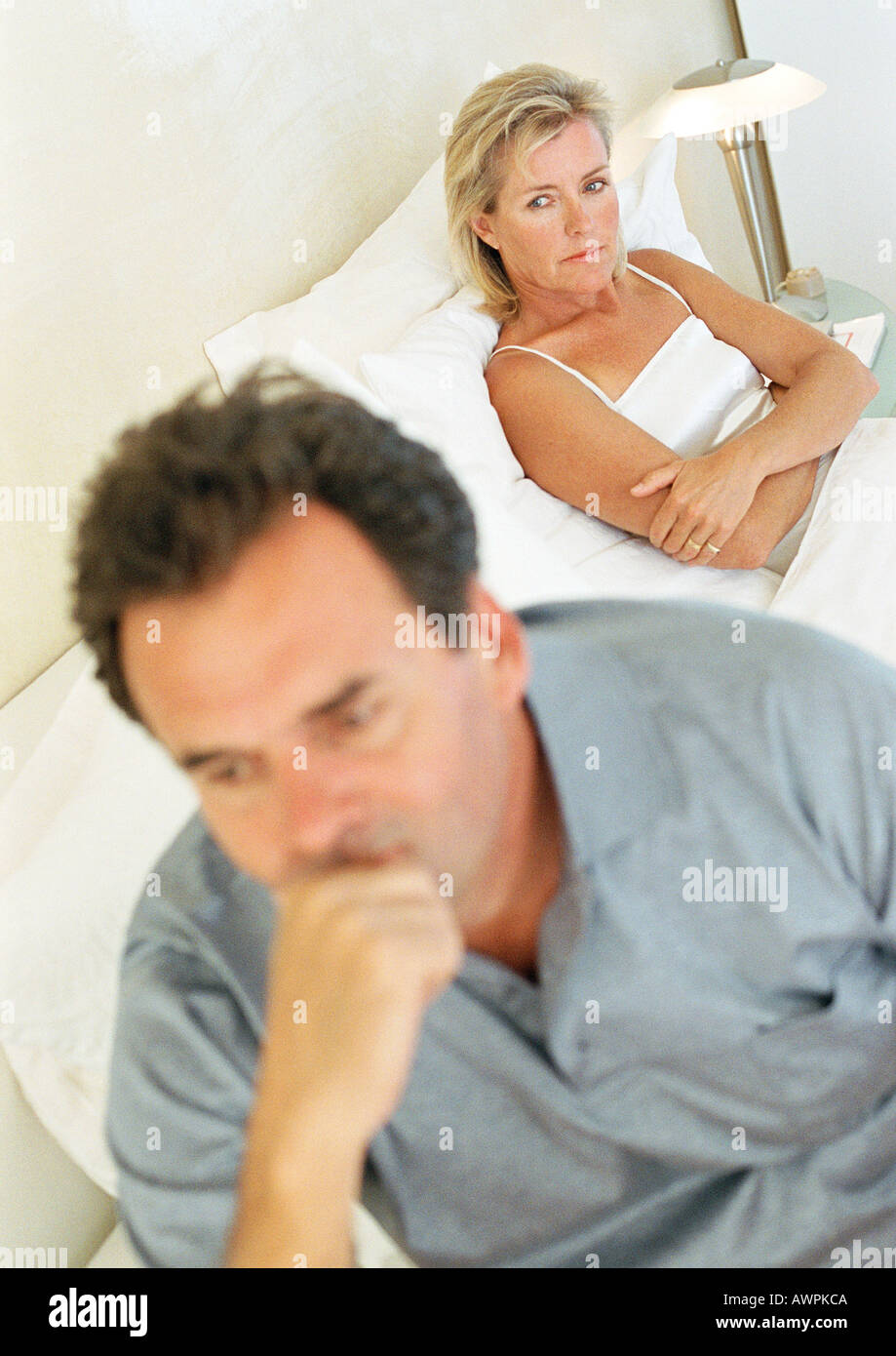 Couple in bed, woman with arms folded, man holding head Stock Photo