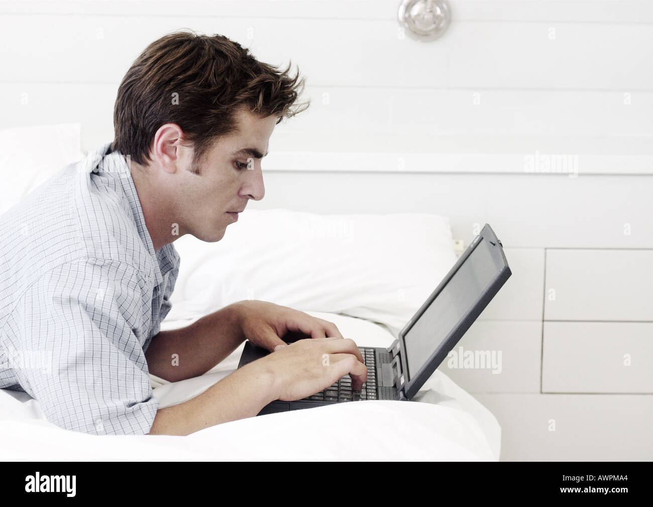 Man lying on stomach, using laptop computer, side view Stock Photo Alamy