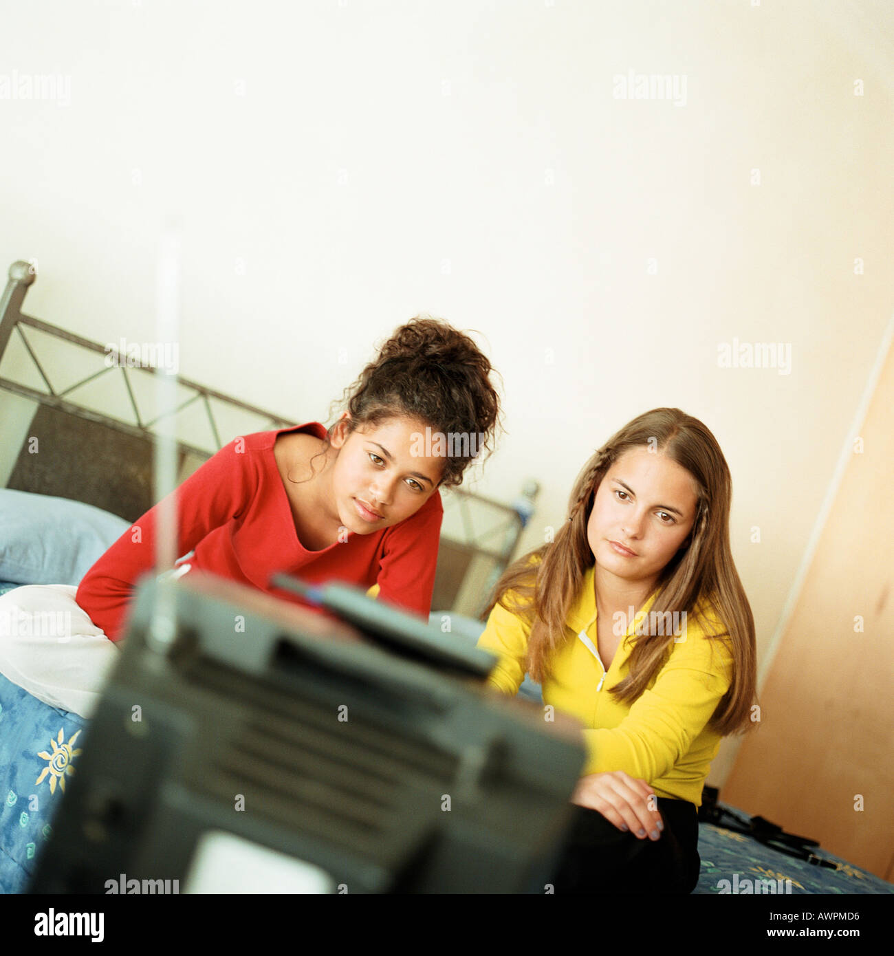 Two girls on bed watching television Stock Photo