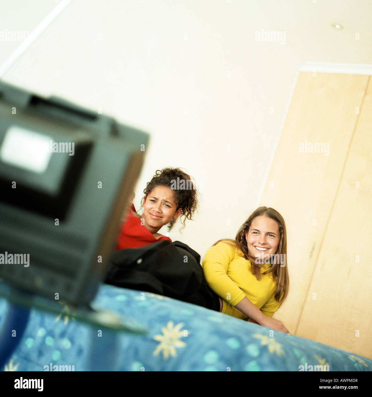 Two girls on bed watching television Stock Photo