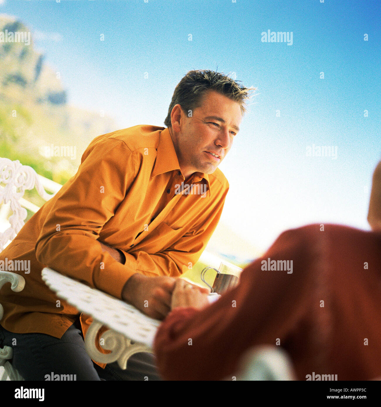 Man sitting at table outside Stock Photo