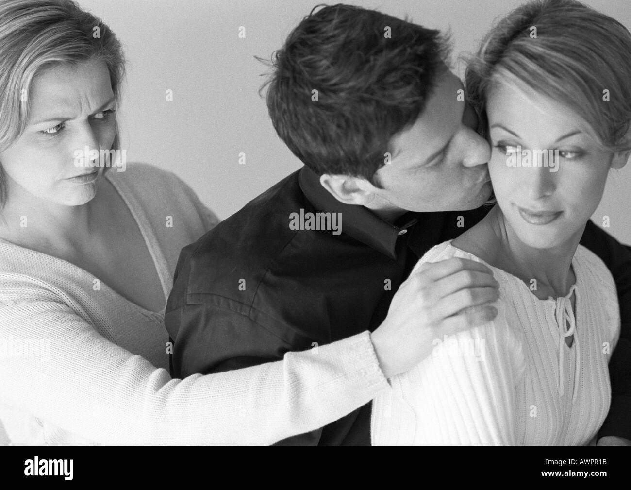 Man standing between two women, kissing one of them, b&w Stock Photo