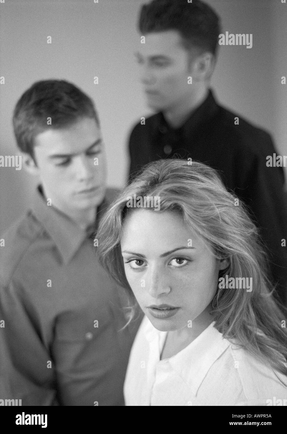 Woman standing in front of two men, portrait, b&w Stock Photo