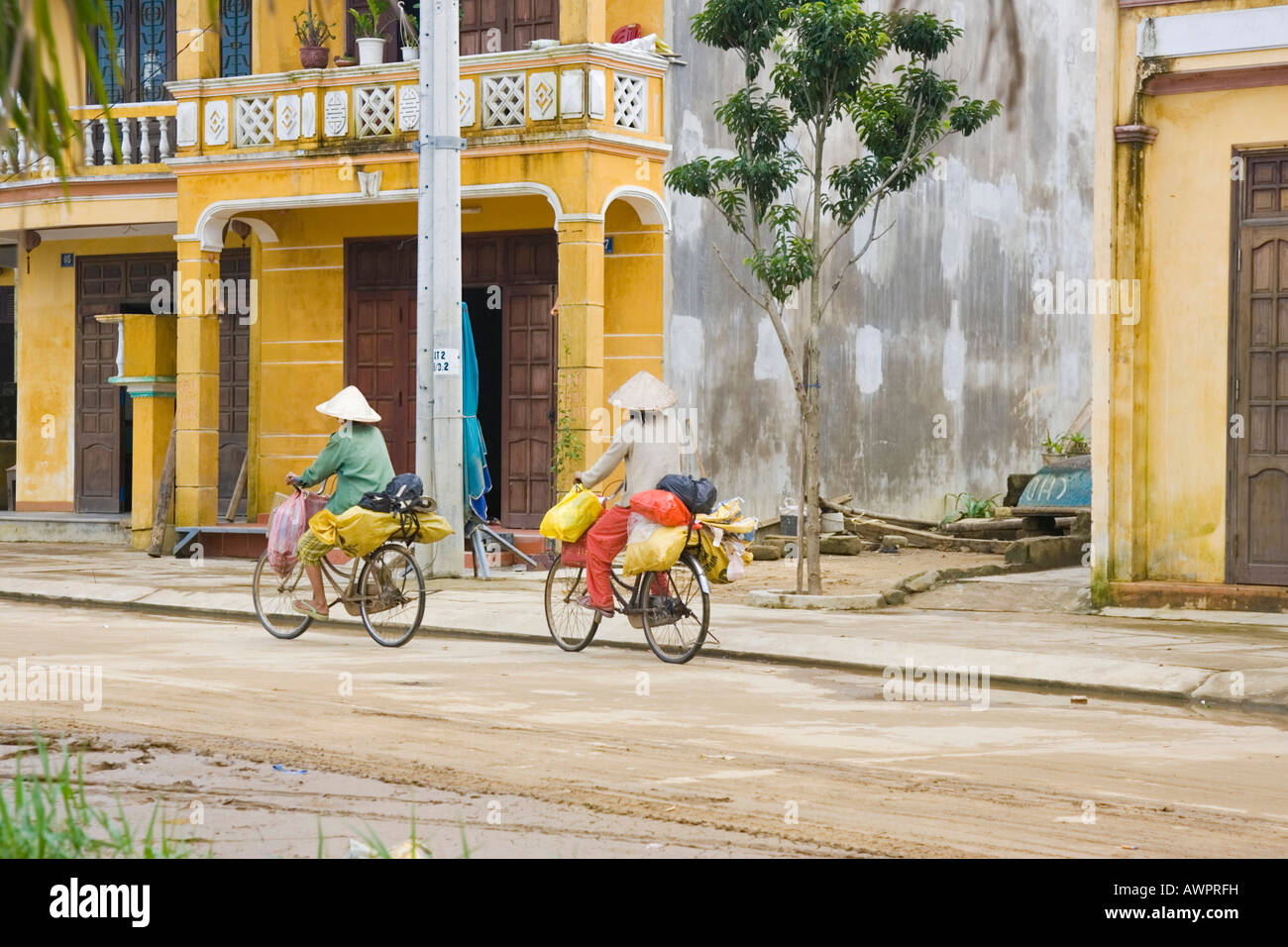 Two Vietnamese women ride by bicycles, Hoi An, Vietnam, Asia Stock Photo