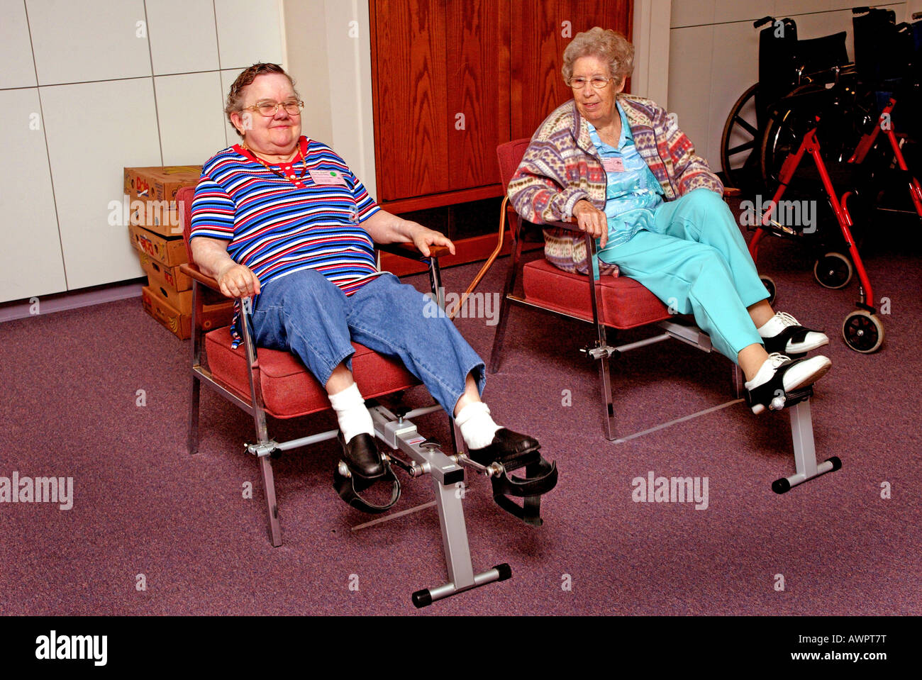 Two Senior Women Exercise On Pedal Machines At Senior Day Care