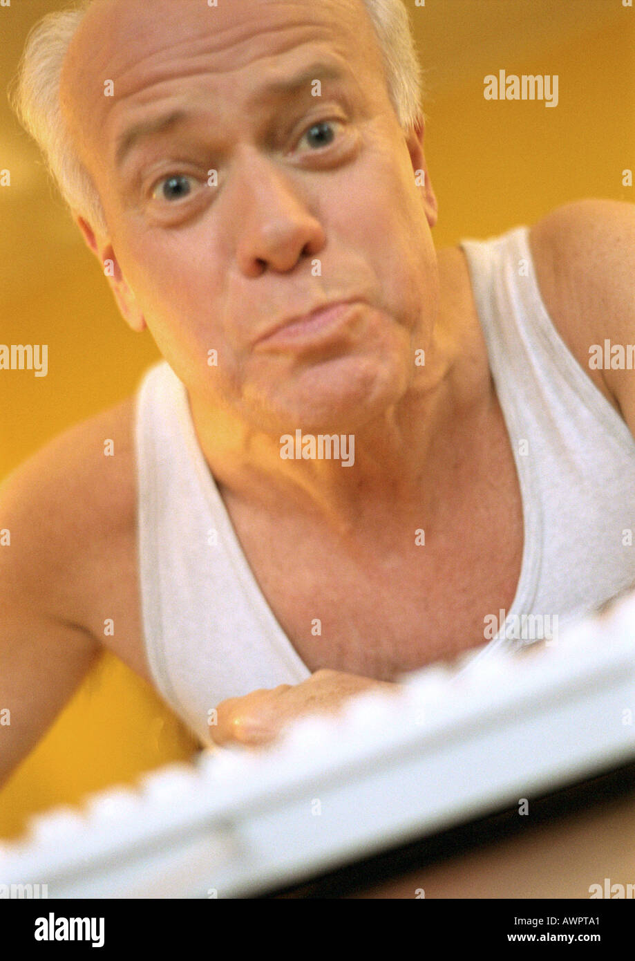 Mature man looking into camera, computer keyboard in foreground, portrait. Stock Photo