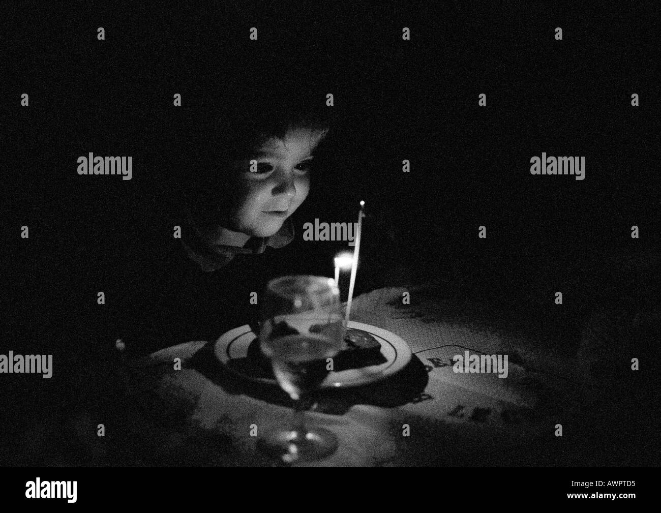 Child sitting at candle lit table, b&w Stock Photo Alamy