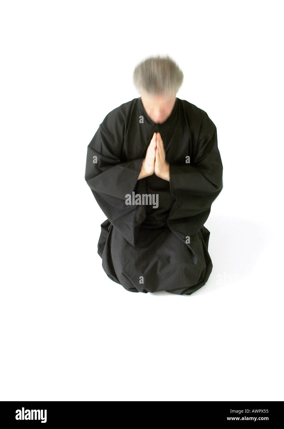 Man kneeling on floor, hands together Stock Photo