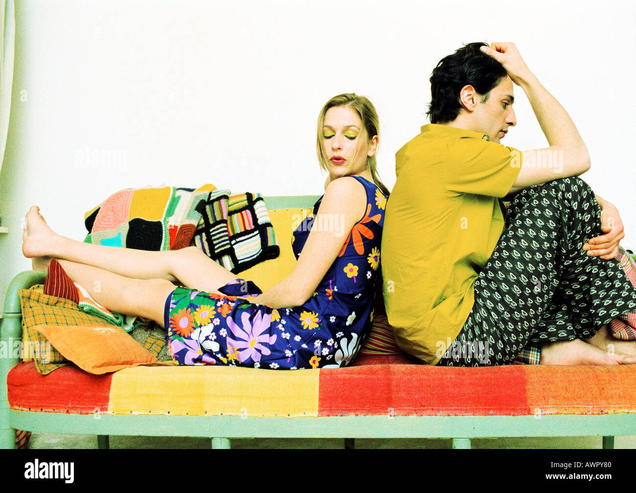 Couple sitting on sofa, back to back. Stock Photo