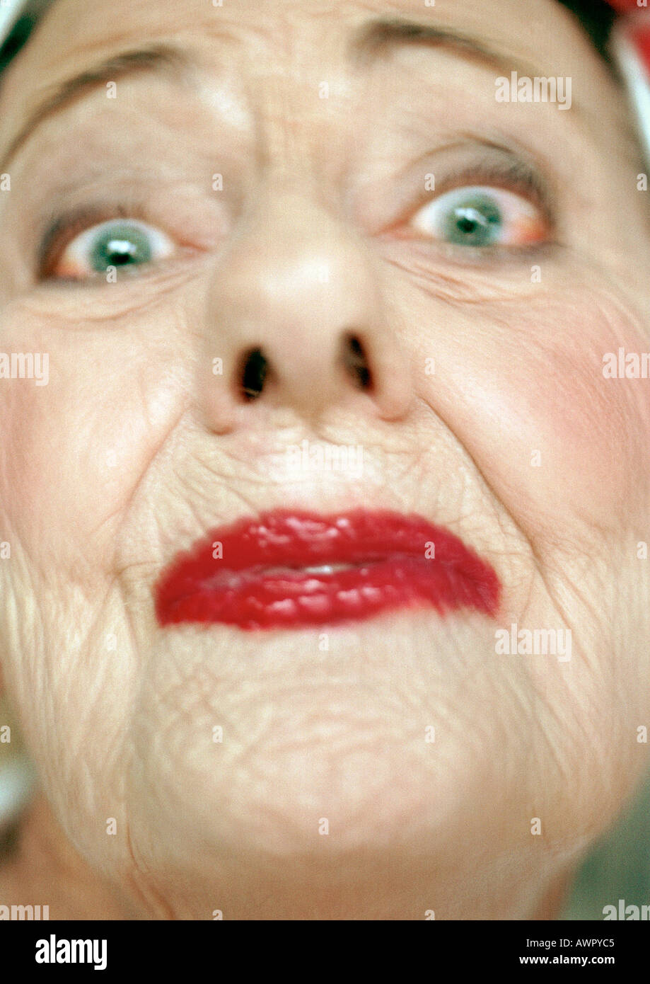 Senior woman wearing red lipstick looking at camera, portrait, extreme close-up Stock Photo