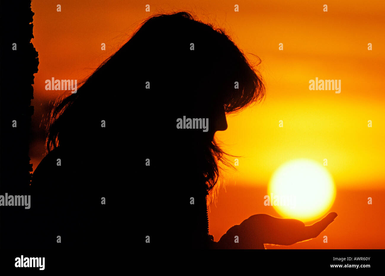 Woman holding the evening sun in her hand Stock Photo - Alamy