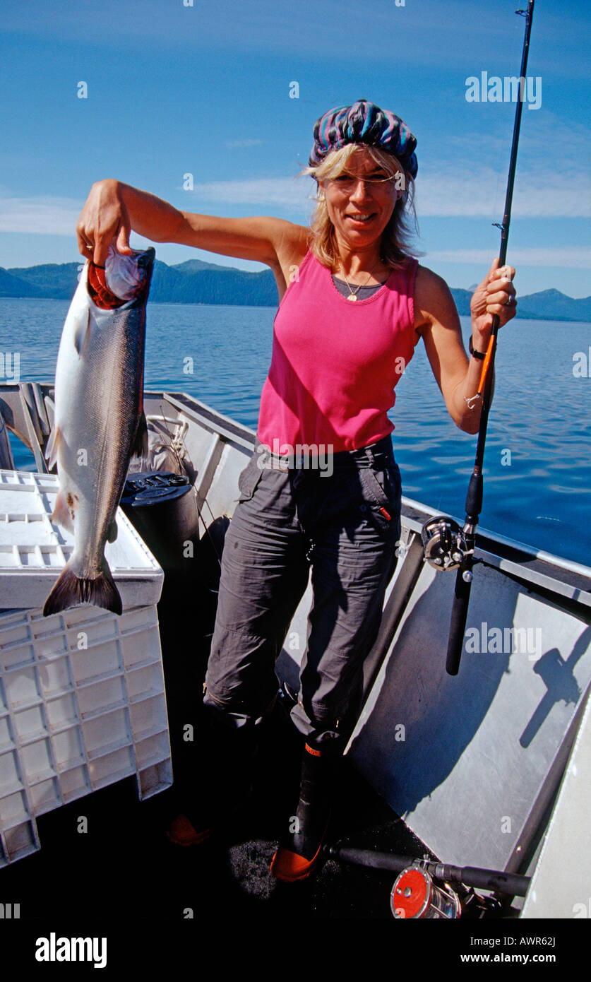 Woman catches a Coho or Silver Salmon (Oncorhynchus kisutch) in Prince William Sound, Alaska, USA Stock Photo