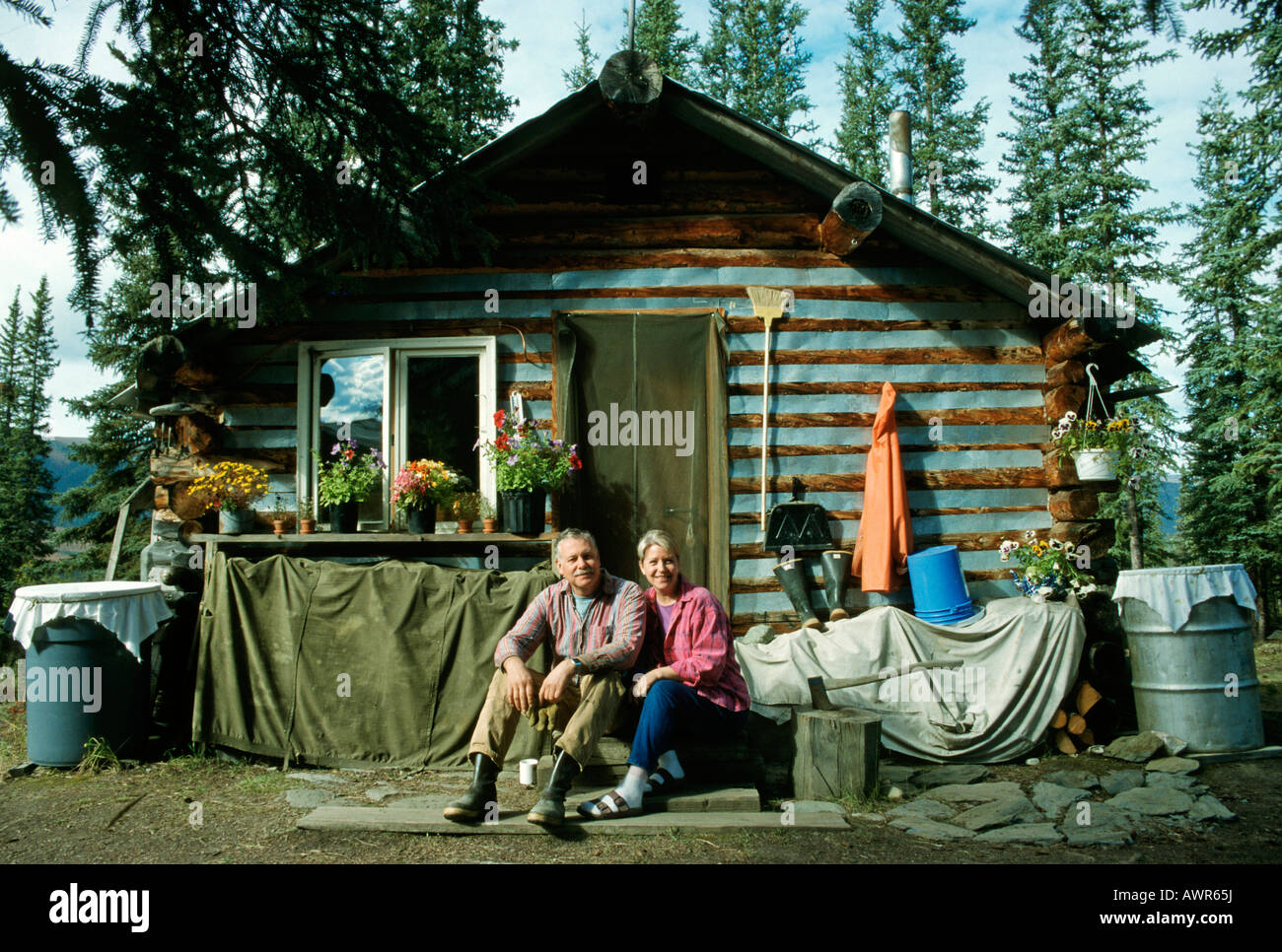 Couple sitting in front of their log home, Brooks Range, Alaska, USA