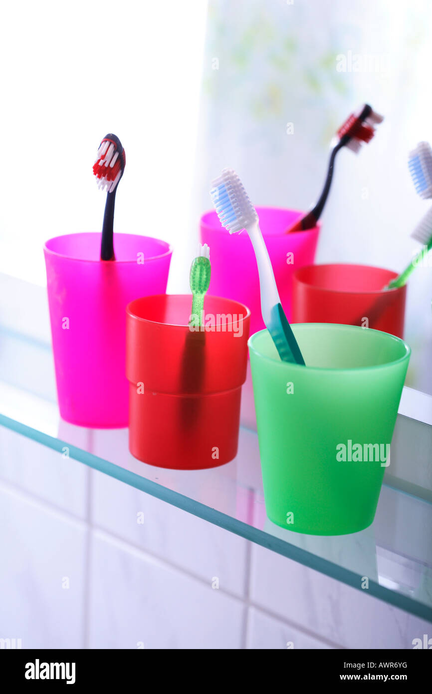 Three toothbrushes in colored toothbrush tumblers Stock Photo