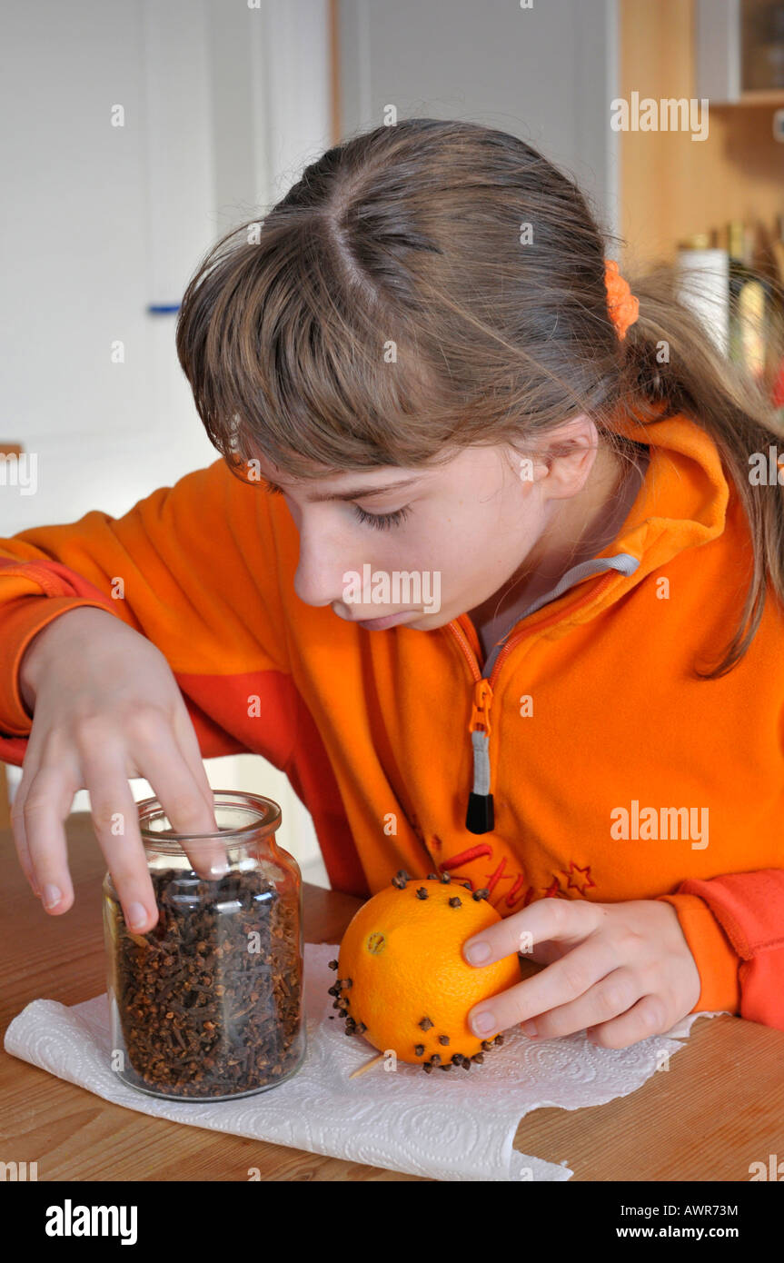 Girl crafting an air freshener from an orange and cloves, pomander Stock Photo