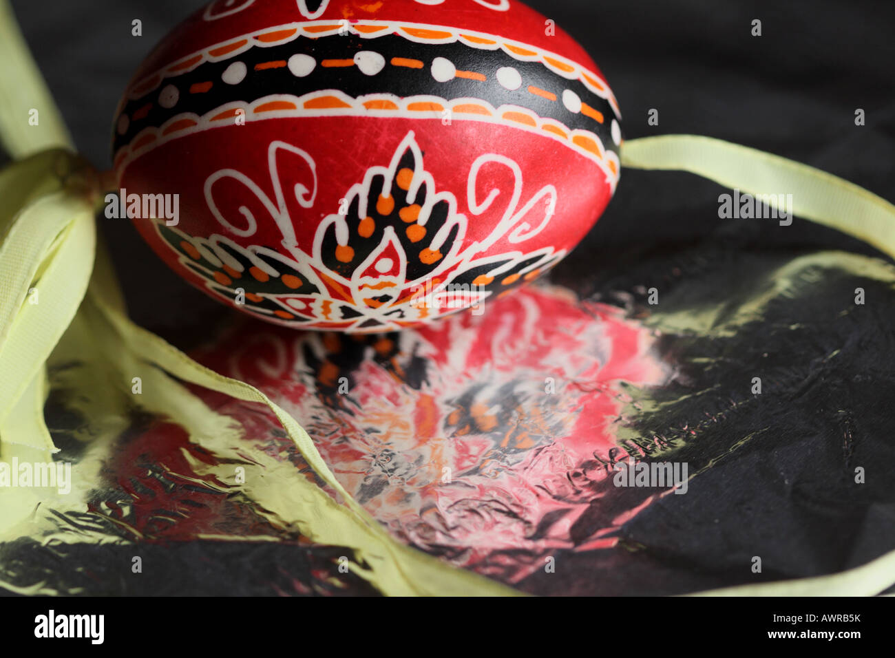 a red and black traditional Czech Easter egg reflects in silver foil Stock Photo